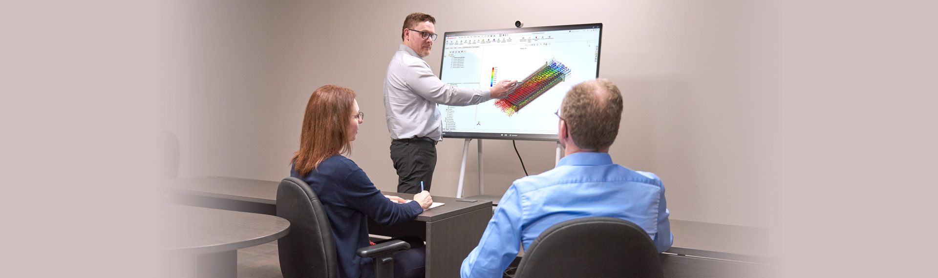 Three Spectra Premium engineers discussing the design of heat exchanger on interactive computer